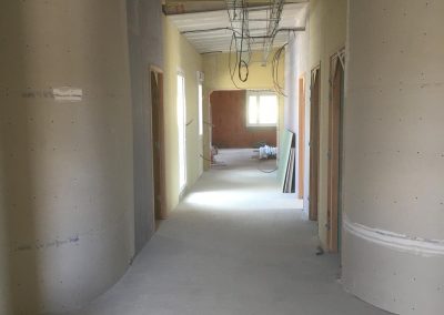 Création de cloisons intérieures en plaques de plâtre dans un couloir, passage des réseaux en cours.